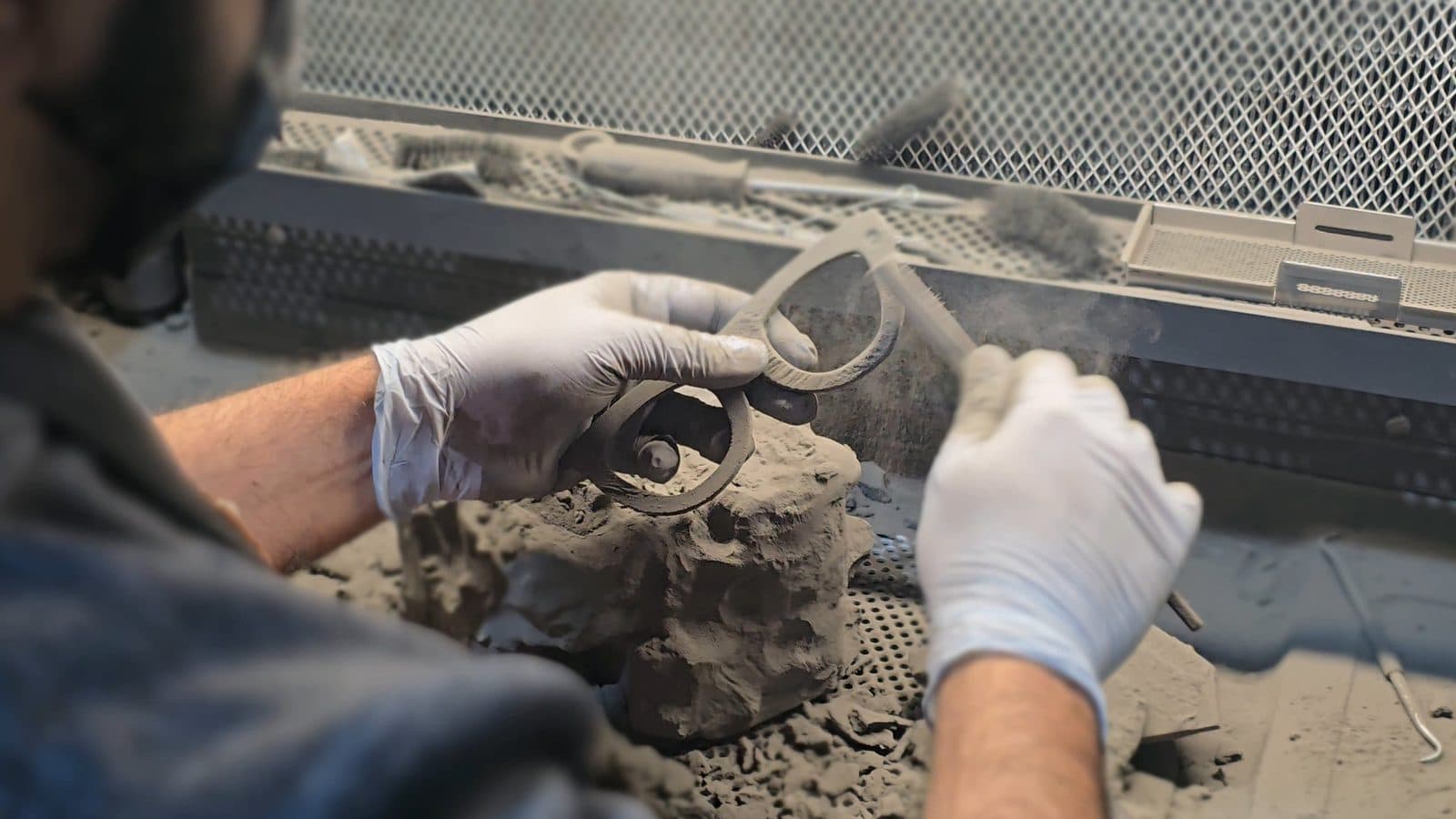 Brushing loose nylon powder off an SLS printed part at the Fuse Sift