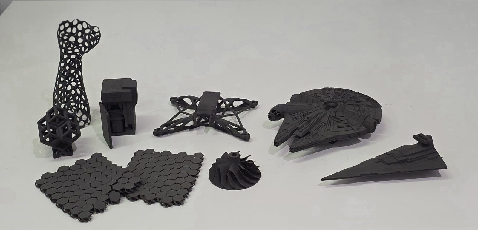 Finished black SLS nylon parts from one build: a lattice, a drone frame, a turbine, chainmail and model spaceships