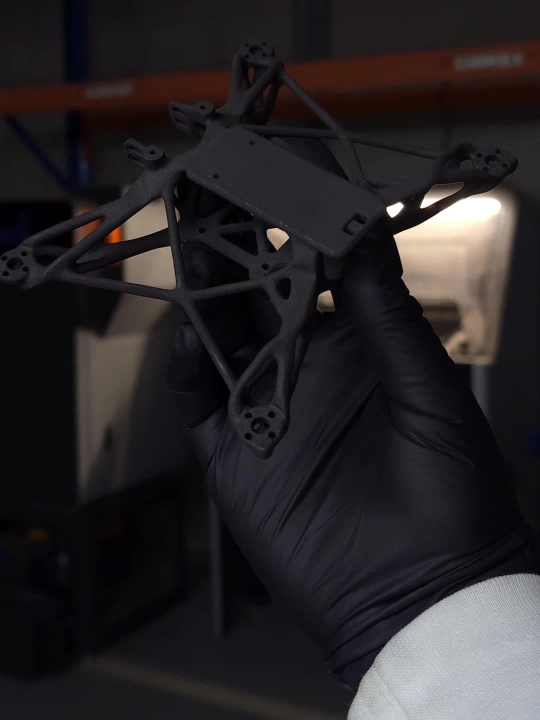 Black Nylon 12 GF drone frame printed with SLS, held in a gloved hand